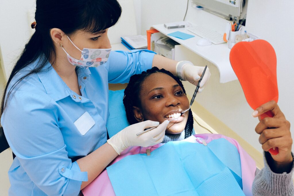 A patient looking at mirror while the dentist examins